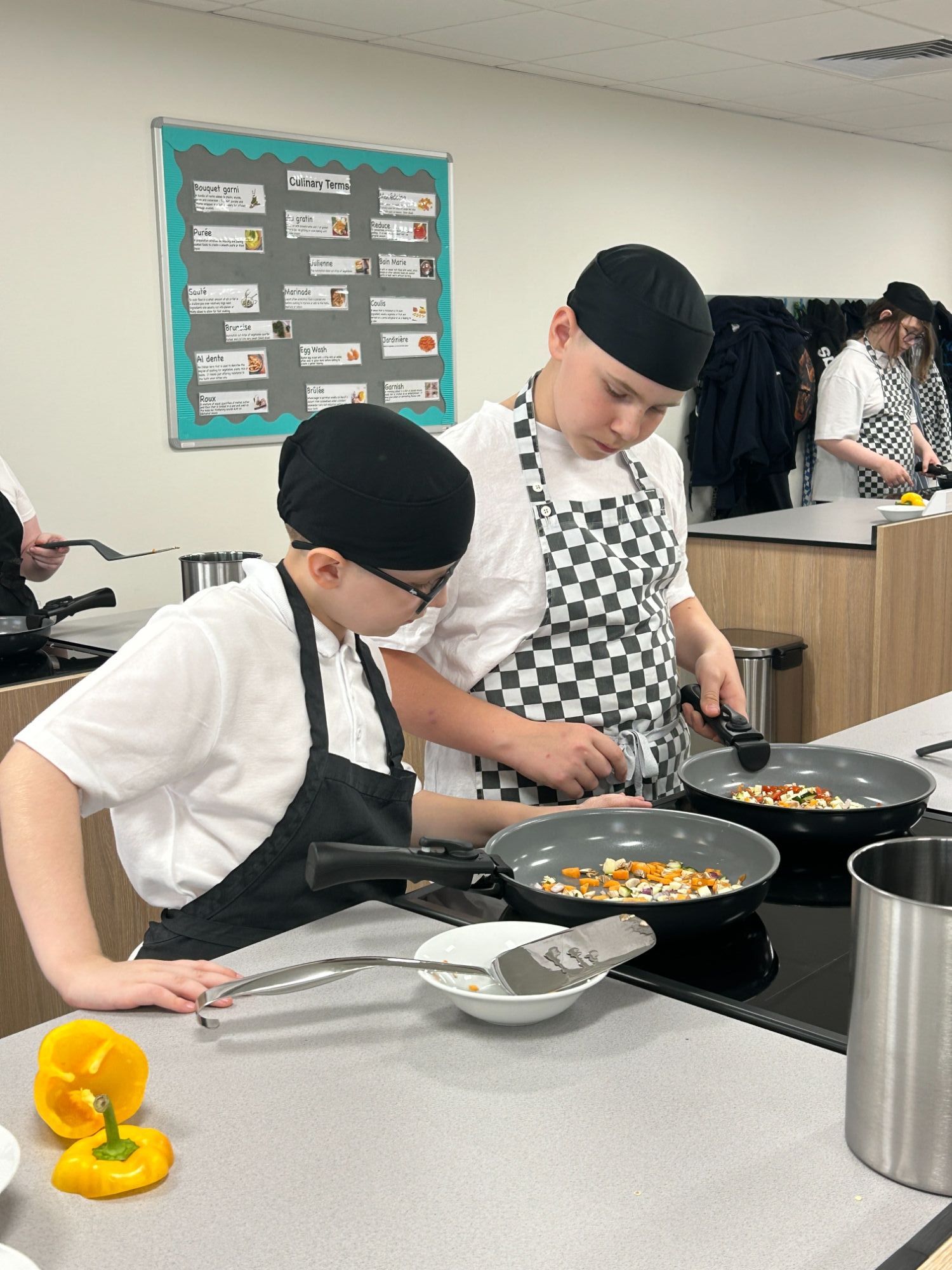 Two students frying on a work station in the new catering room