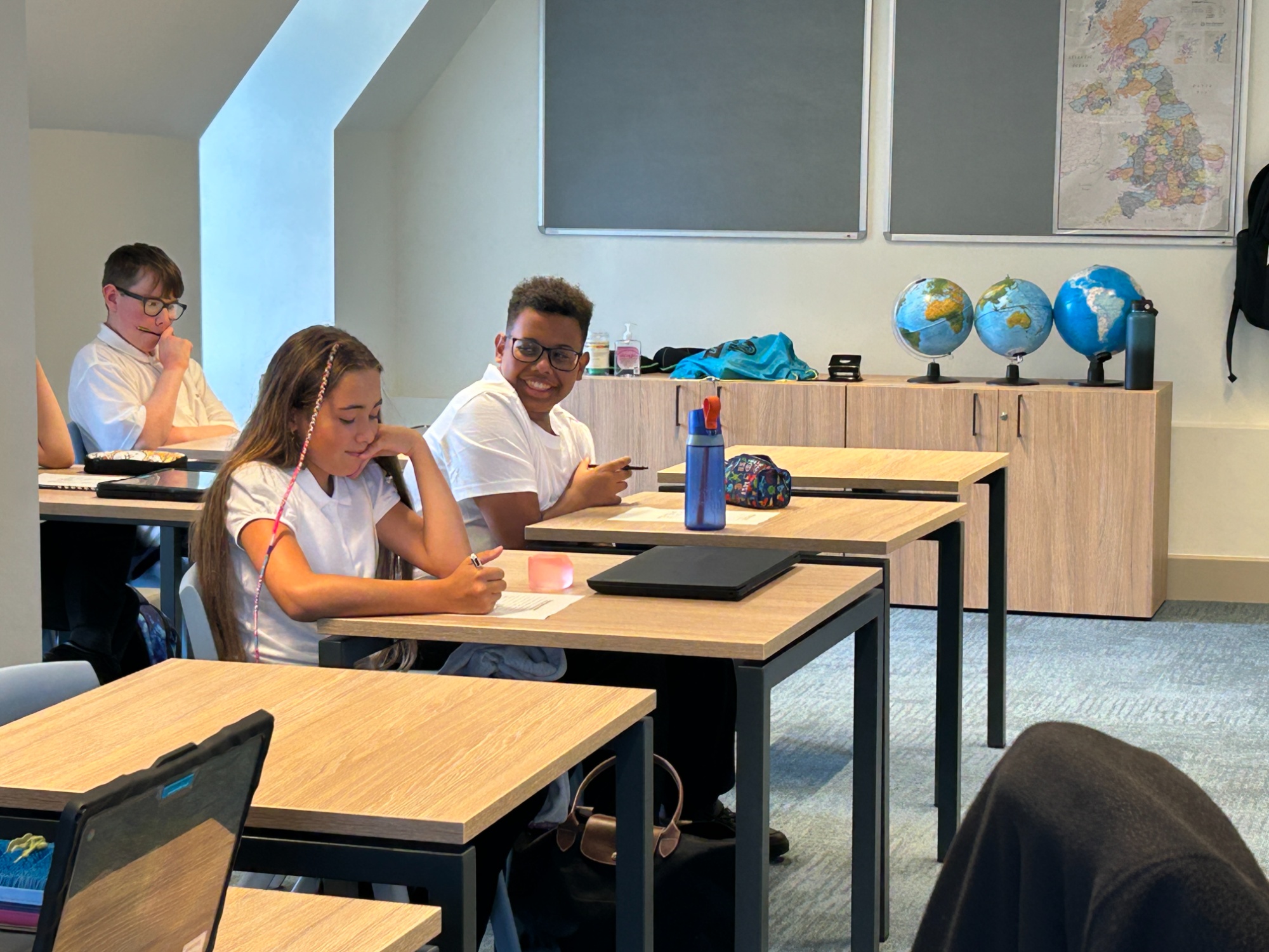 Three students smiling studying at desks in a new flexible classroom