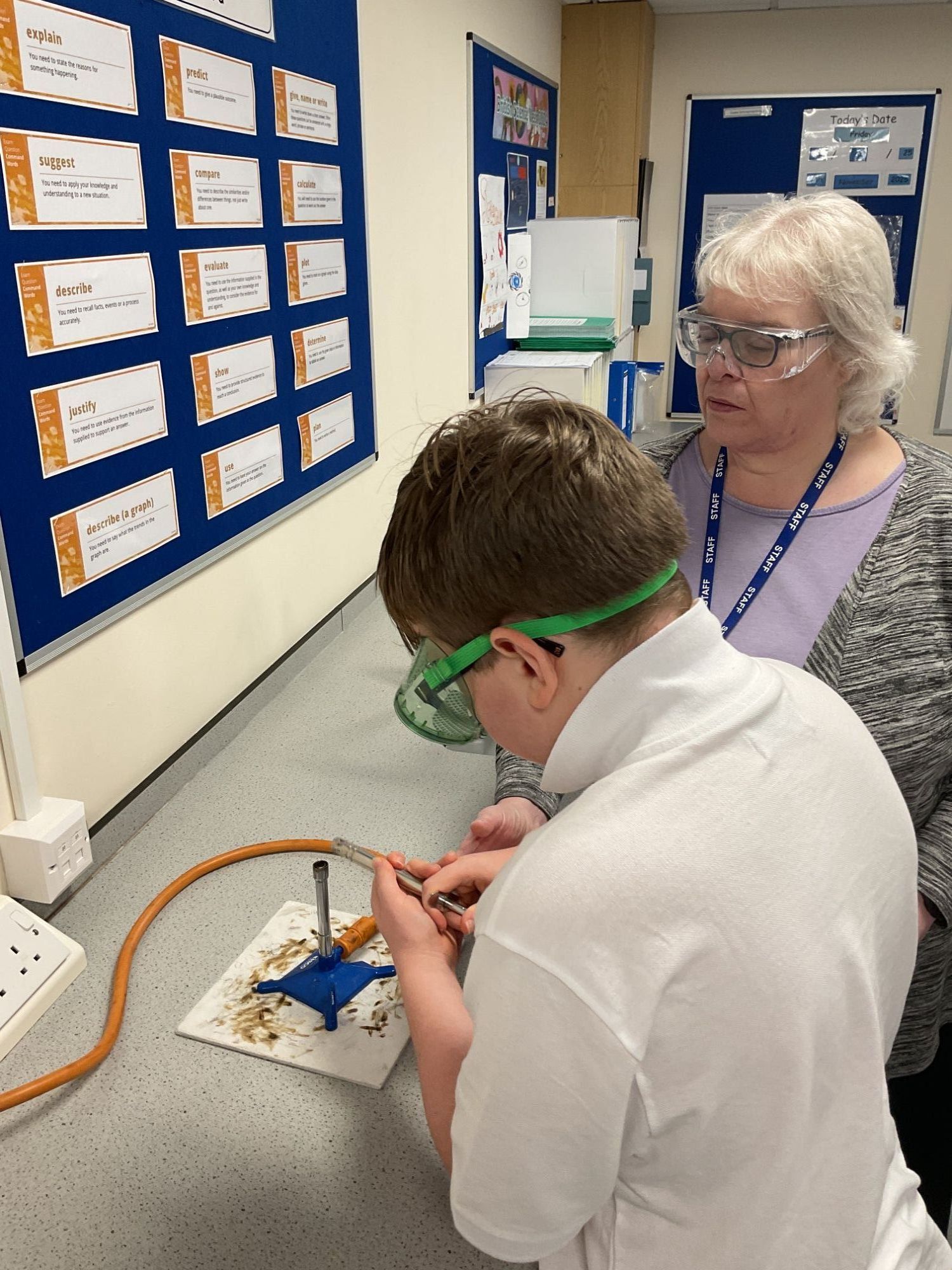 Teacher helping student set up a Bunsen burner