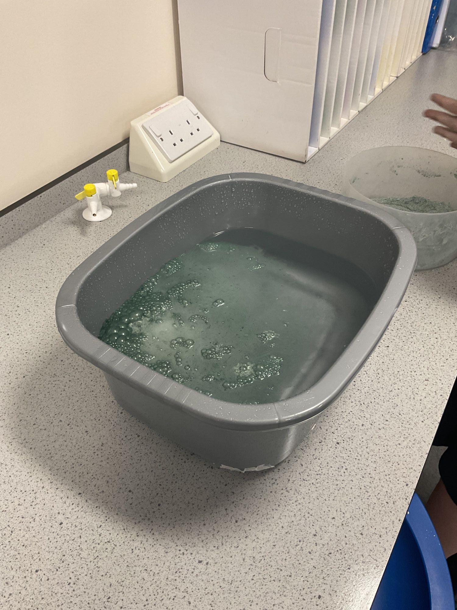 Close-up of a bath bomb fizzing in a washing-up bowl full of water