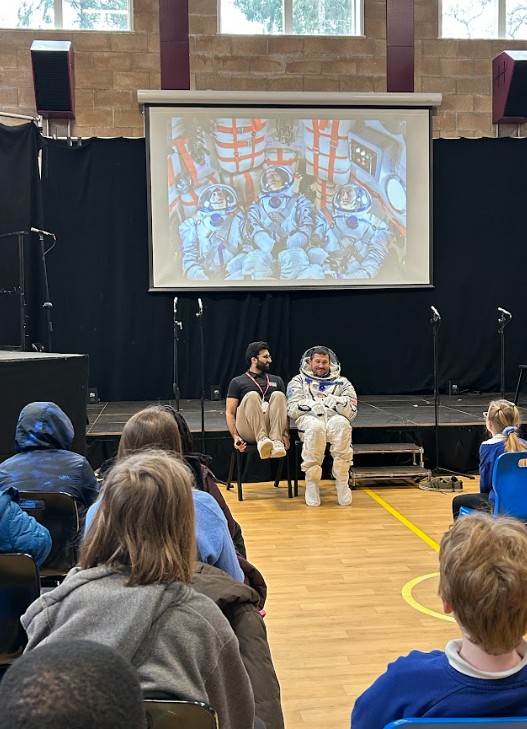 Pete and speaker demonstrating how astronauts sit in the rocket