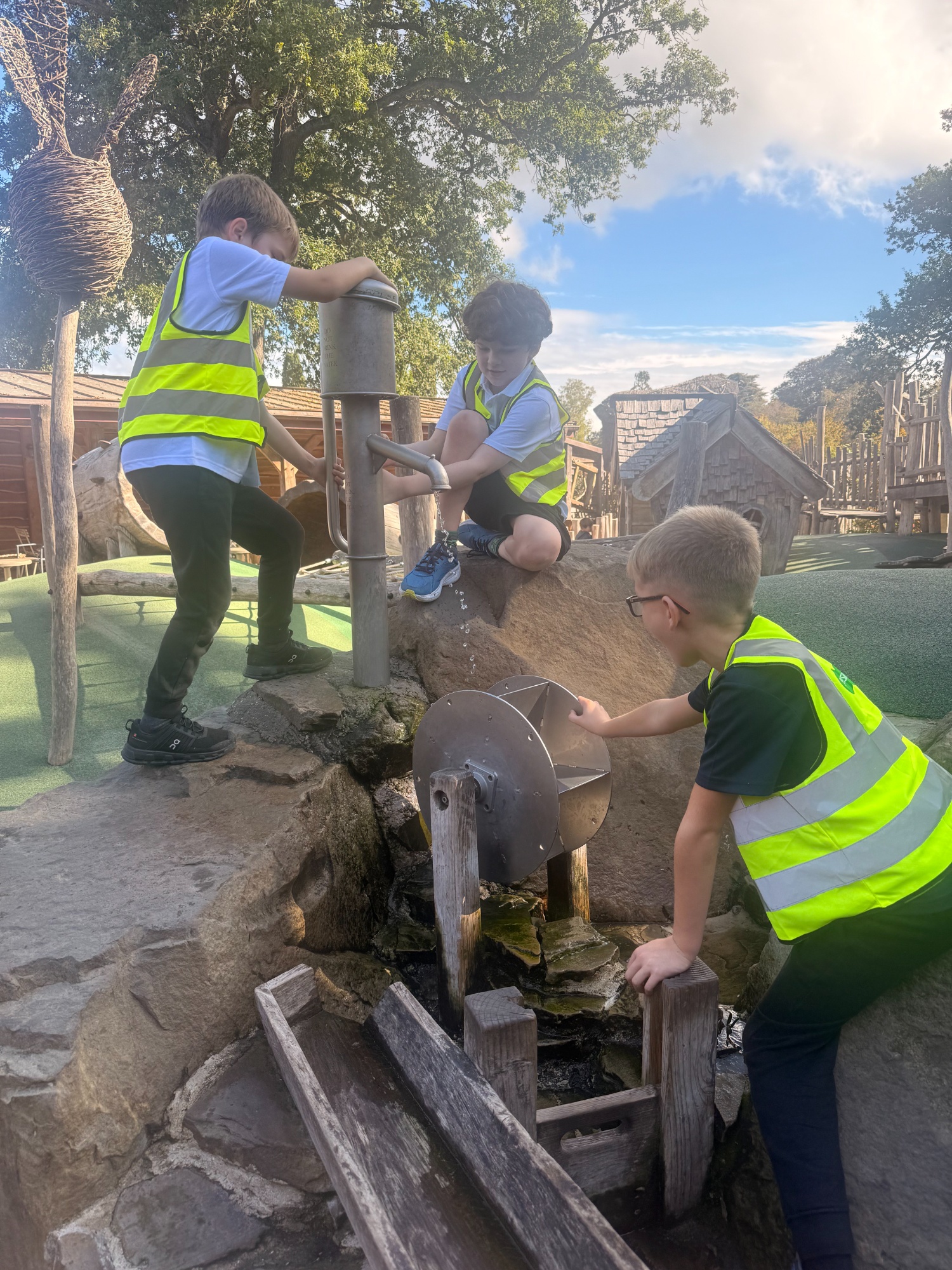 Three boys working together to pump water through play equipment