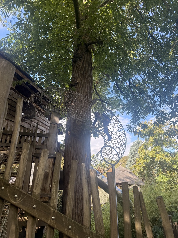 Child climbing through a mesh tunnel into a tree house