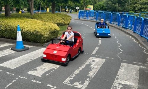 Students driving lego cards on track at park