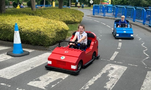 Students driving lego cards on track at park