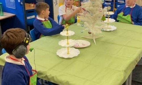 Oak class in their aprons sat at the table they have decorated for the cafe 