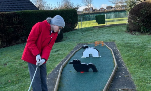 Student about to hit his golf ball at one of the holes