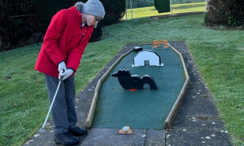 Student about to hit his golf ball at one of the holes