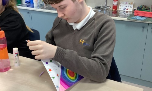 Member of Earth class about to fold their art work into a windmill.