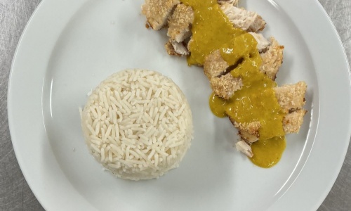 Finished chicken katsu curry (breaded chicked drizzled with sauce and a neat circle of rice)