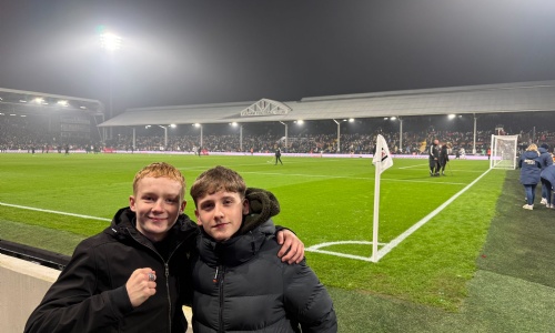Two students with their arms round each other in front of the pitch