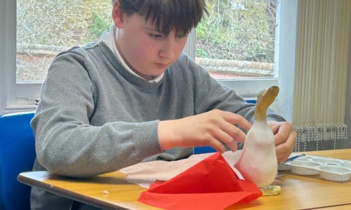 Student adding tissue paper to his Mother's Day duck