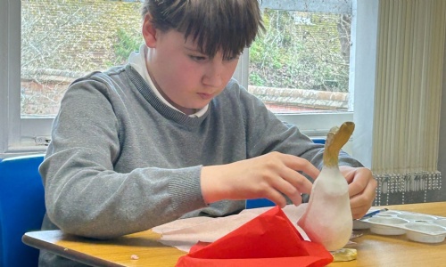 Student adding tissue paper to his Mother's Day duck