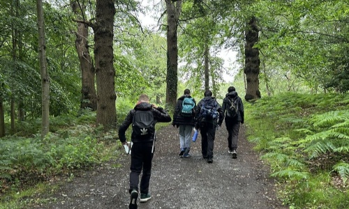 Group of four students with ruck sacks on walking through a forest