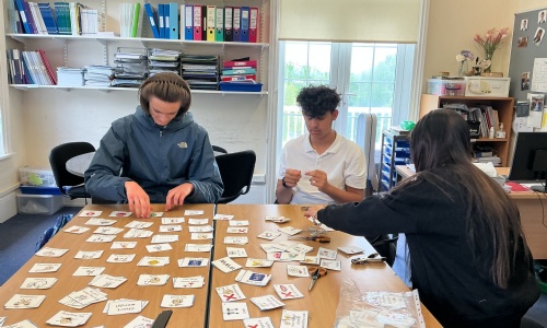 Three students sat at a desk helping to sort out papers for school