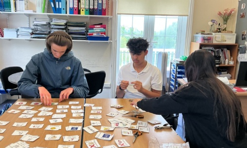 Three students sat at a desk helping to sort out papers for school