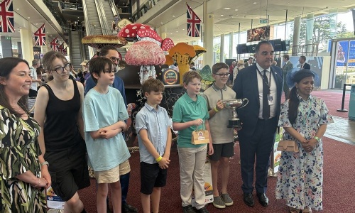 Students stood in front of their artwork holding their trophy and prize