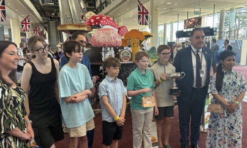 Students stood in front of their artwork holding their trophy and prize