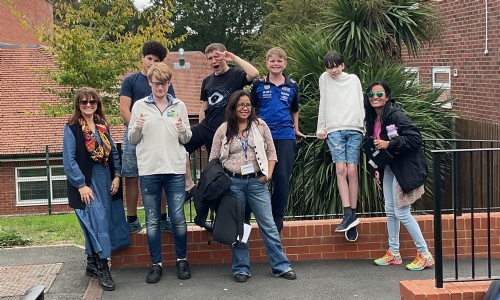 A small group of students and staff smiling wearing their jeans outside the modular building